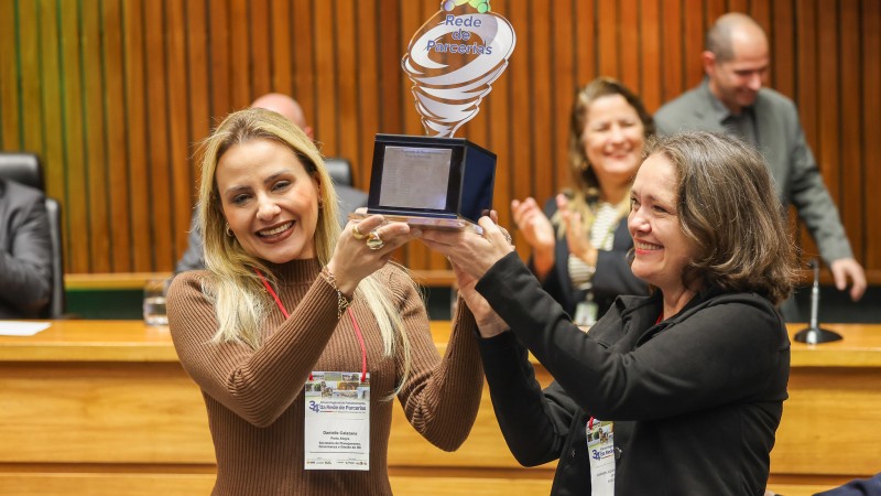 Secretária Danielle Calazans e diretora do DECAP/SPGG, Carmen Juçara Nunes, recebem o troféu que simboliza a Rede de Parcerias