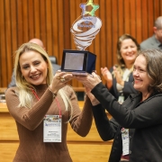 Secretária Danielle Calazans e diretora do DECAP/SPGG, Carmen Juçara Nunes, recebem o troféu que simboliza a Rede de Parcerias